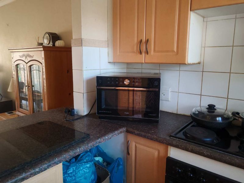 A dated kitchen area featuring laminate cabinetry, tiled splashbacks, and built-in cooking appliances, offering potential for a modern renovation.