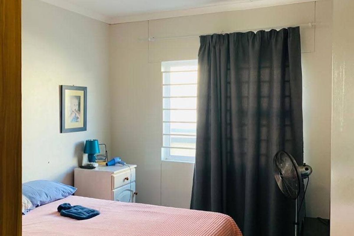 A bedroom featuring tiled flooring, a window with fitted curtain tracks, and a central ceiling light fixture.