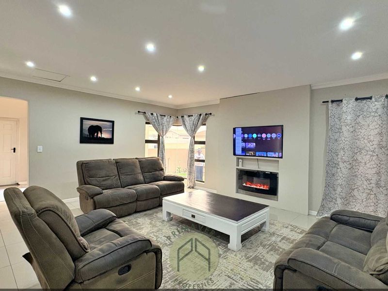 Spacious living room featuring tiled flooring, recessed downlighting, and a modern built-in electric fireplace with a wall-mounted television.