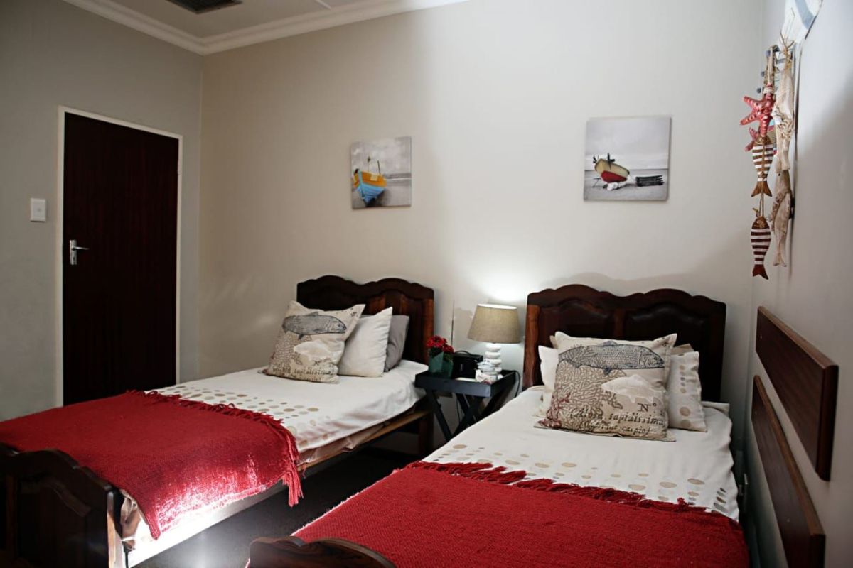 A bedroom featuring two single beds, neutral wall tones, and a dark wood door, providing a functional and comfortable sleeping space.