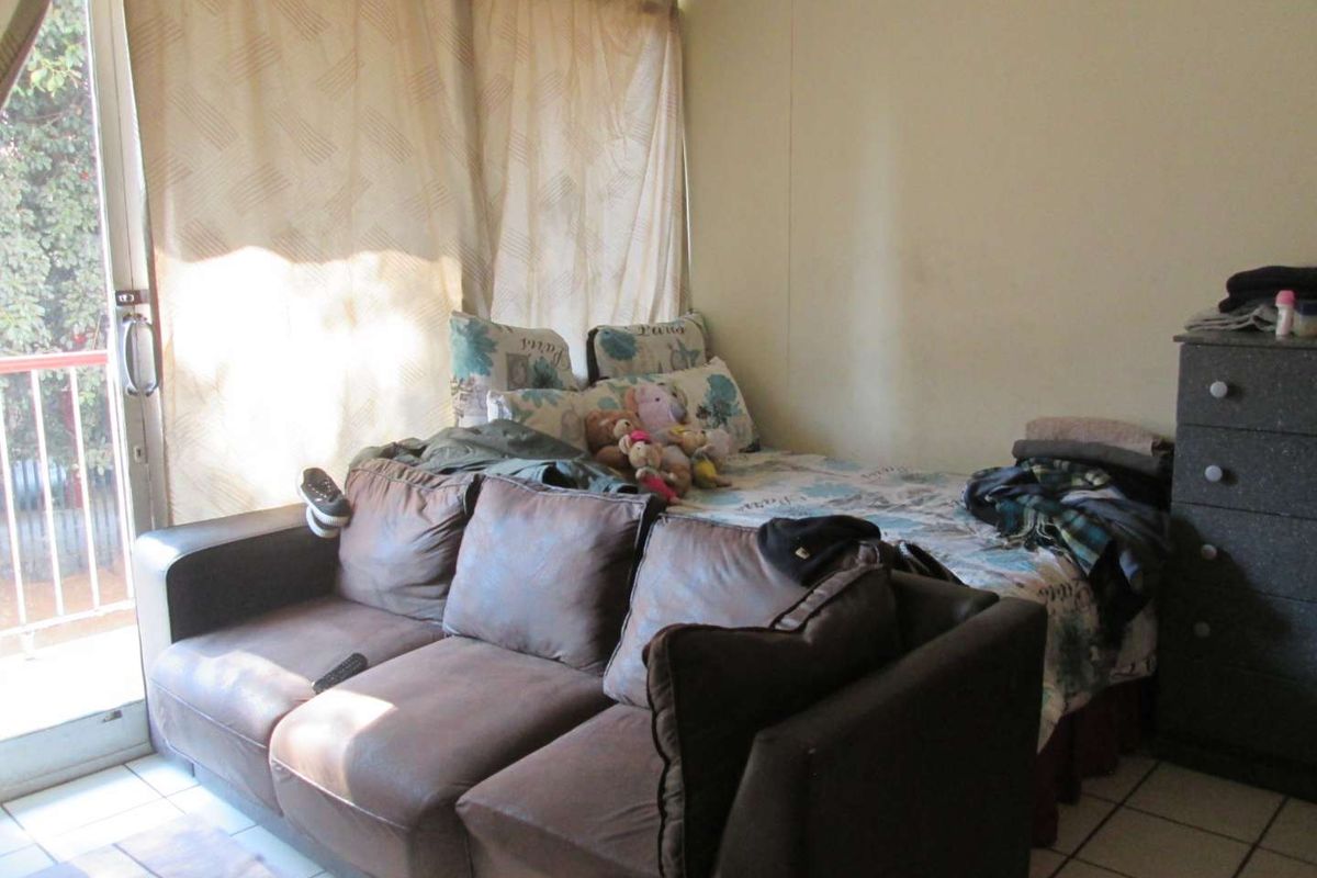 A bedroom featuring tiled flooring and a sliding glass door providing access to a balcony, offering natural light and outdoor connectivity.
