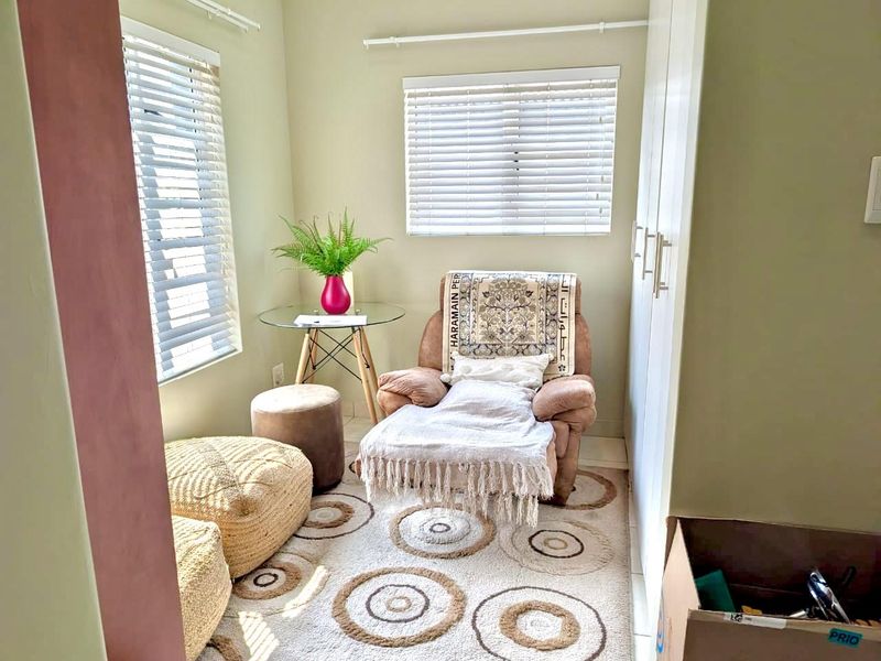 A compact bedroom featuring built-in cupboards and dual windows with venetian blinds, offering a bright and functional space.