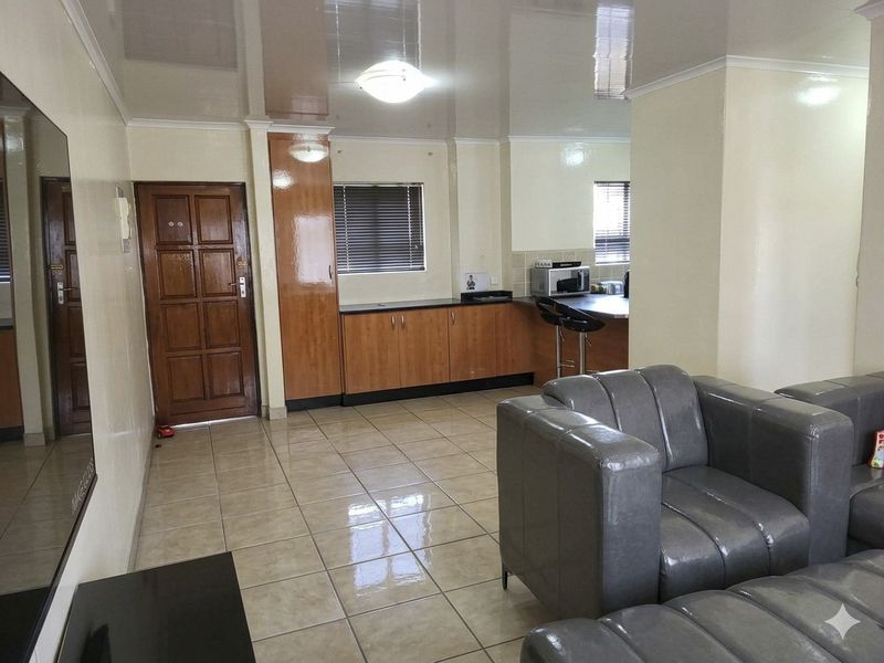 Open plan living and kitchen area featuring tiled flooring, built-in cabinetry, and a breakfast counter in a functional apartment layout.