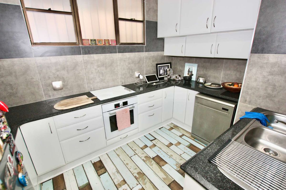 A functional kitchen featuring white cabinetry, dark granite countertops, a built-in oven, and a stainless steel dishwasher.