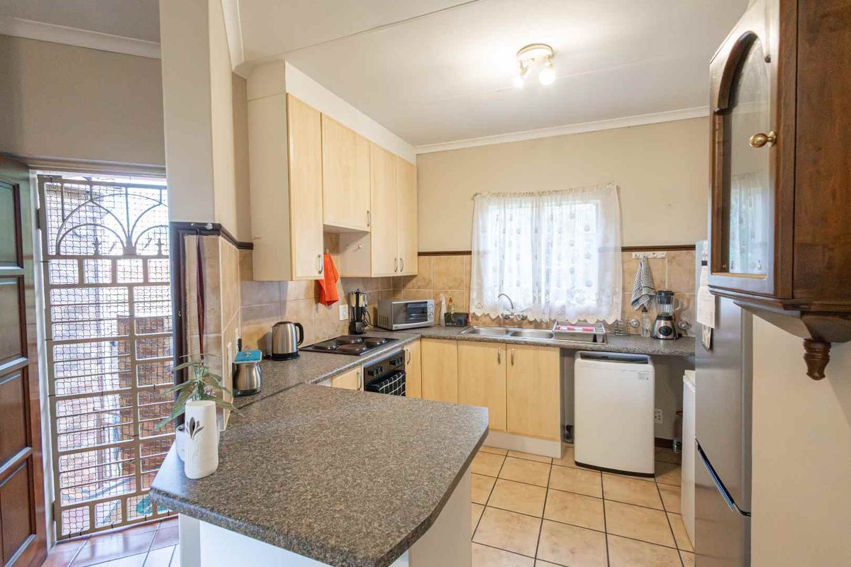 Functional kitchen featuring light wood cabinetry, granite-look laminate countertops, tiled flooring, and a breakfast bar counter.