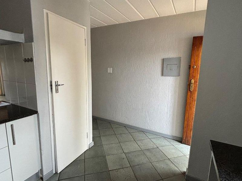A functional kitchen area featuring tiled flooring, built-in cabinetry with dark countertops, and a panelled ceiling, presenting a clean, empty space ready for updates.