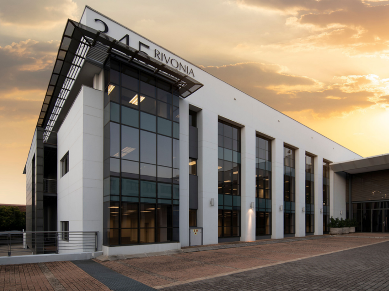 Modern multi-story office building facade featuring extensive glass curtain walling and a paved entrance area at 245 Rivonia.