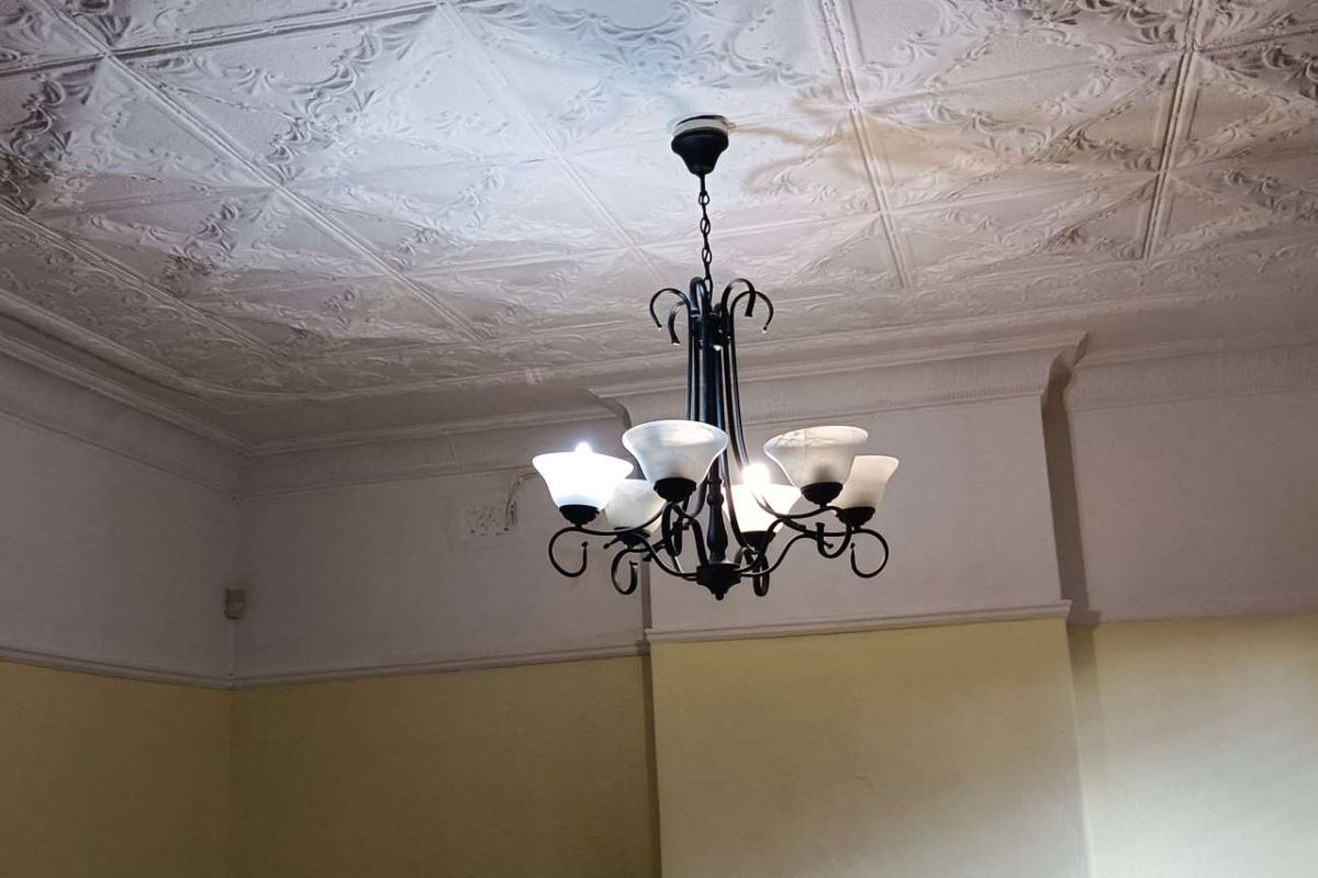 A room featuring a classic pressed metal ceiling, ornate cornice detailing, and a central chandelier, providing a character-filled space.