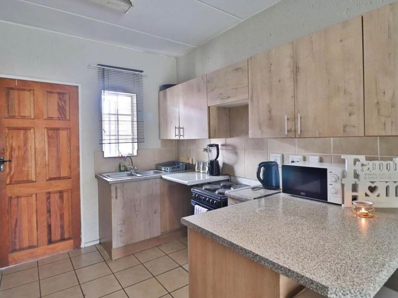 A functional kitchen featuring laminate cabinetry, granite countertops, tiled flooring, and a tiled backsplash, providing a practical workspace for daily meal preparation.