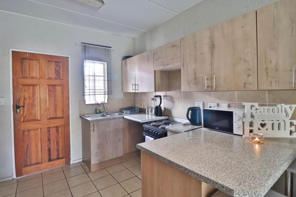 A functional kitchen featuring laminate cabinetry, granite countertops, tiled flooring, and a tiled backsplash, providing a practical workspace for daily meal preparation.
