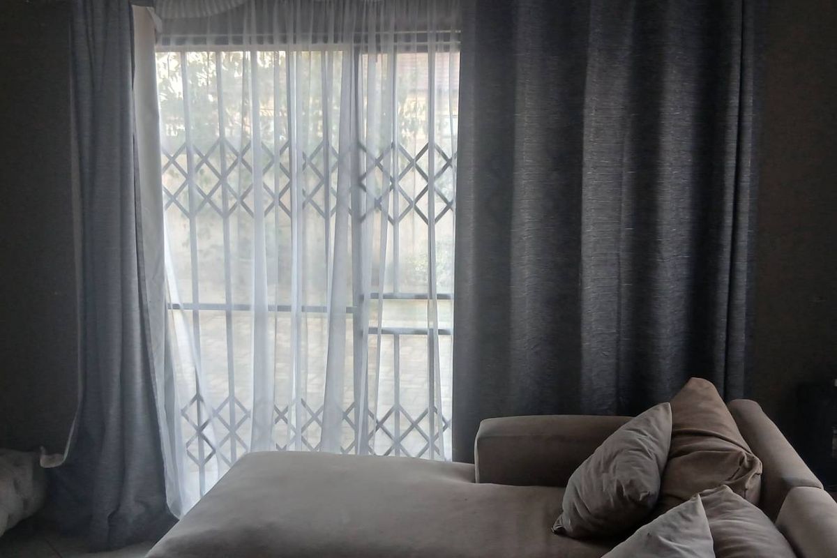 A living room area featuring a sliding glass door with a security gate, providing access to the exterior.