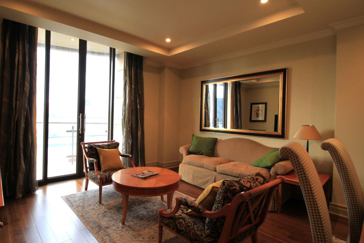 A well-maintained living room featuring recessed ceiling lighting, hardwood flooring, and large glass sliding doors leading to an outdoor balcony area.
