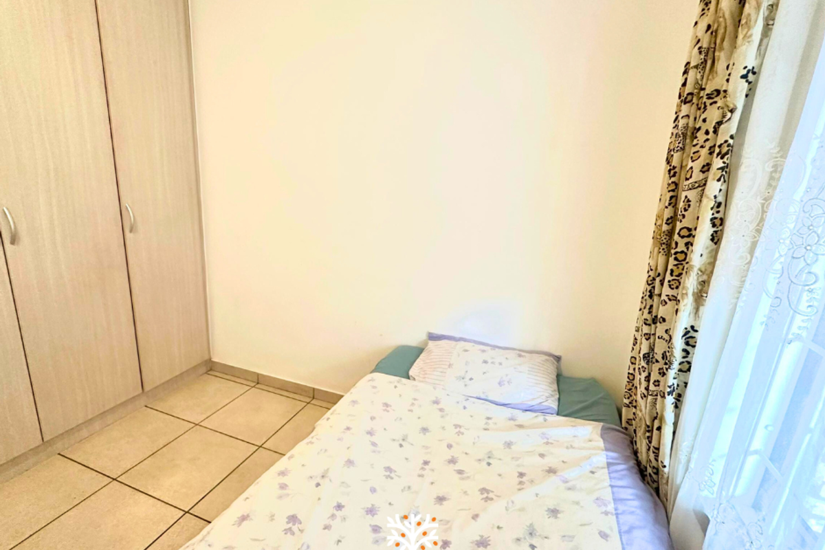 A bedroom featuring built-in cupboards and tiled flooring, providing a functional and neutral living space.