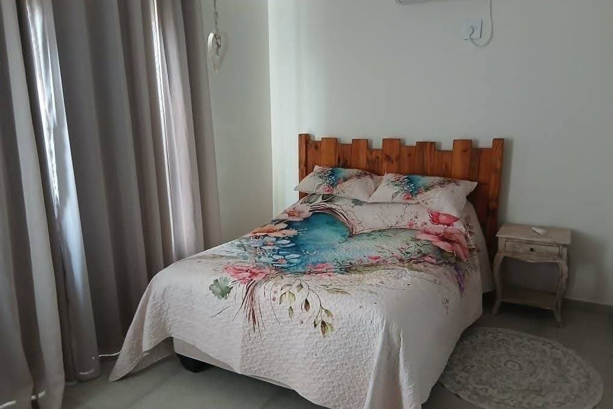 A functional bedroom featuring tiled flooring and a wall-mounted split-system air conditioner for climate control.