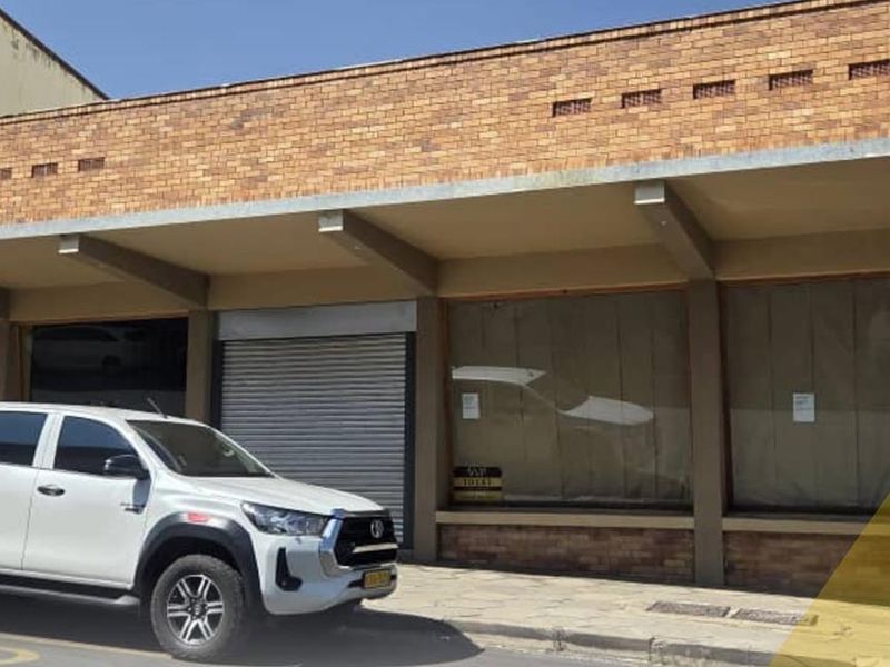Front exterior view of a commercial property featuring a brick facade, large display windows, and a secure metal roller shutter entrance.