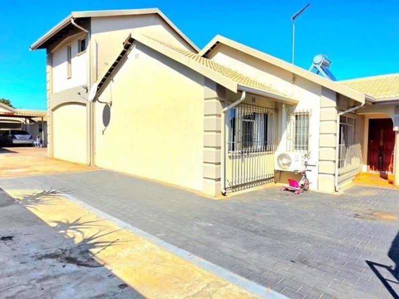 Front view of the property featuring a paved driveway, double garage, and exterior security bars on windows.