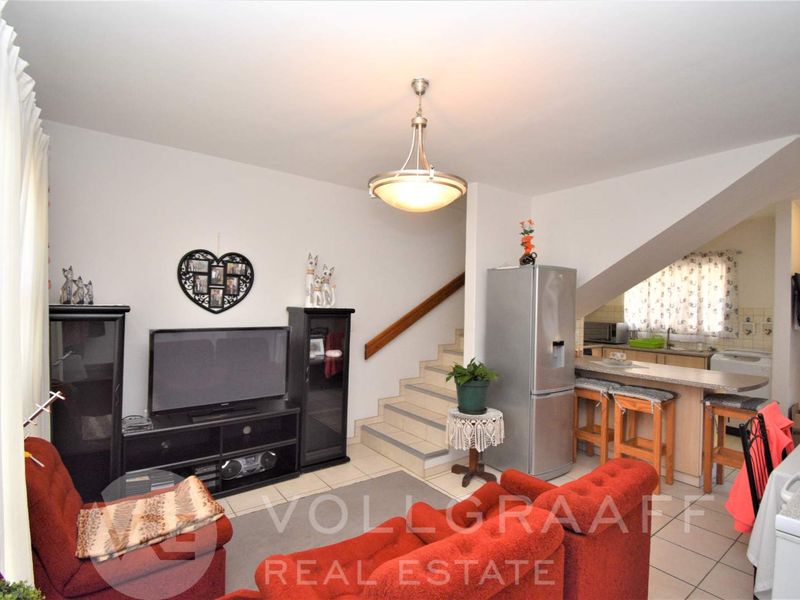 Open plan living area featuring tiled floors, a breakfast bar, and an integrated staircase leading to the upper level.