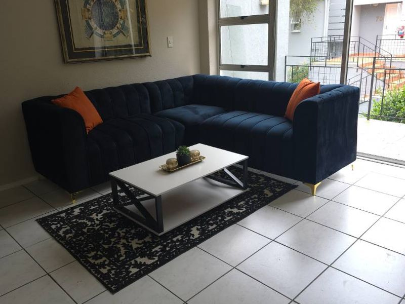 A bright living room featuring neutral tiled flooring and a large sliding glass door providing natural light and access to the exterior.