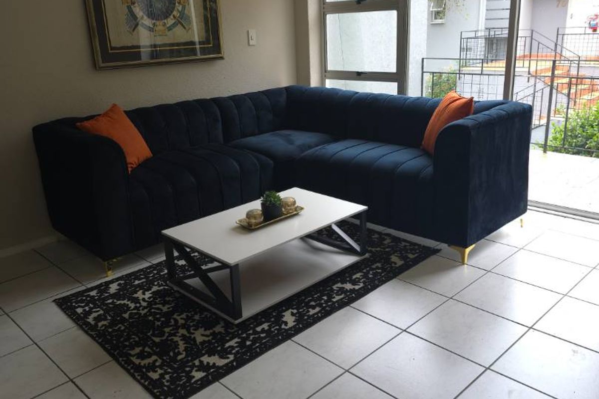 A bright living room featuring neutral tiled flooring and a large sliding glass door providing natural light and access to the exterior.