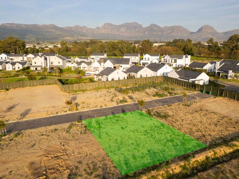 Aerial view of a vacant residential plot in a developed estate, featuring mountain views and established surrounding infrastructure.