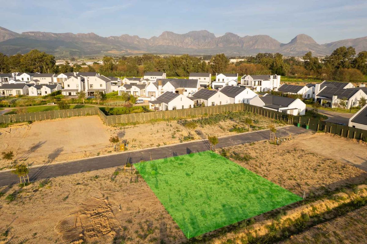 Aerial view of a vacant residential plot in a developed estate, featuring mountain views and established surrounding infrastructure.