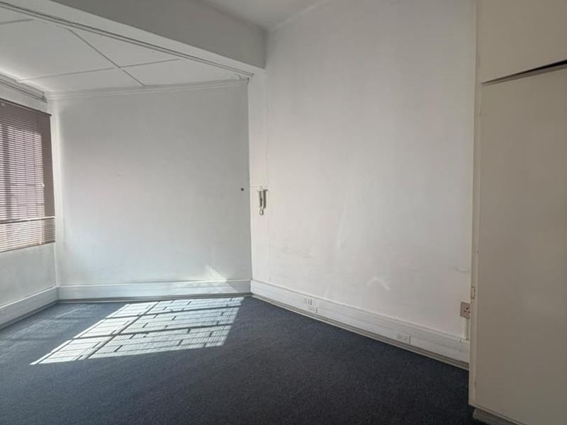 An empty bedroom featuring built-in cupboards, carpet flooring, and natural light through venetian blinds, offering a blank canvas for renovation.