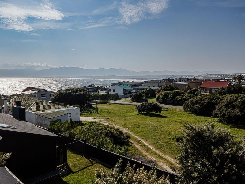 Elevated coastal view overlooking the surrounding residential neighbourhood, green space, and distant mountain range.