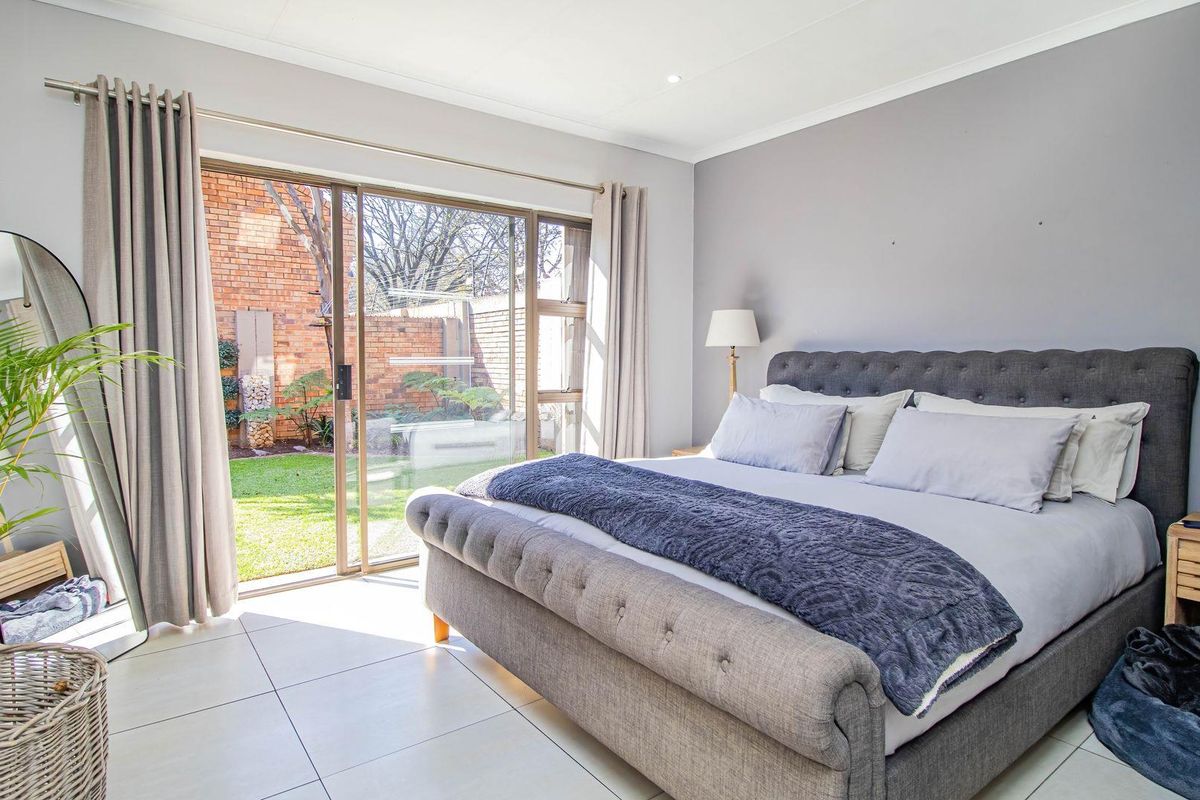 Spacious bedroom featuring tiled flooring, recessed lighting, and a large sliding glass door providing direct access to the rear garden.