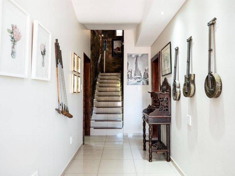 A bright and well-maintained hallway featuring tiled flooring, recessed lighting, and a staircase leading to an upper level with a stone feature wall.