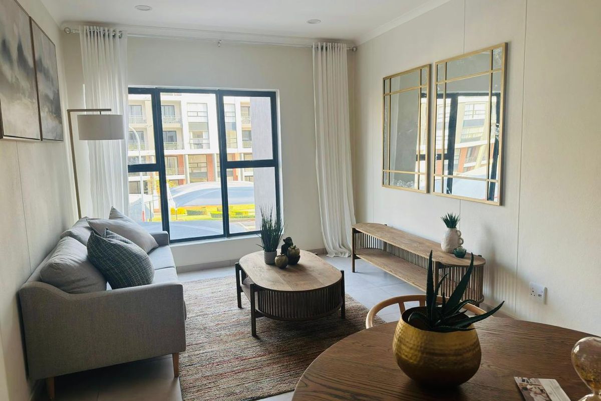 A bright and modern living area featuring large windows, tiled flooring, and recessed ceiling lighting, creating a comfortable and inviting space.