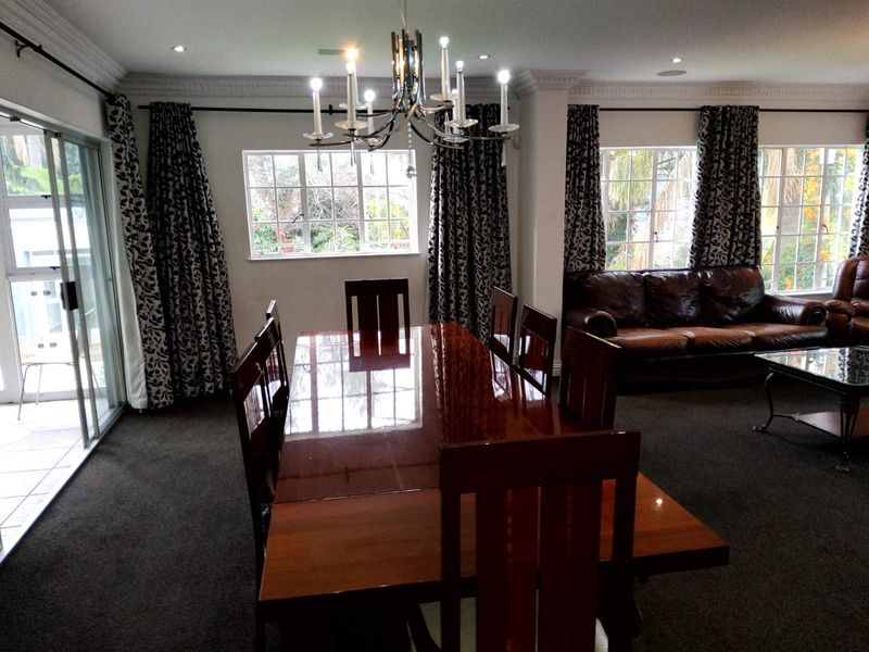 Spacious dining area featuring crown molding, recessed lighting, and large windows providing natural light and garden views.