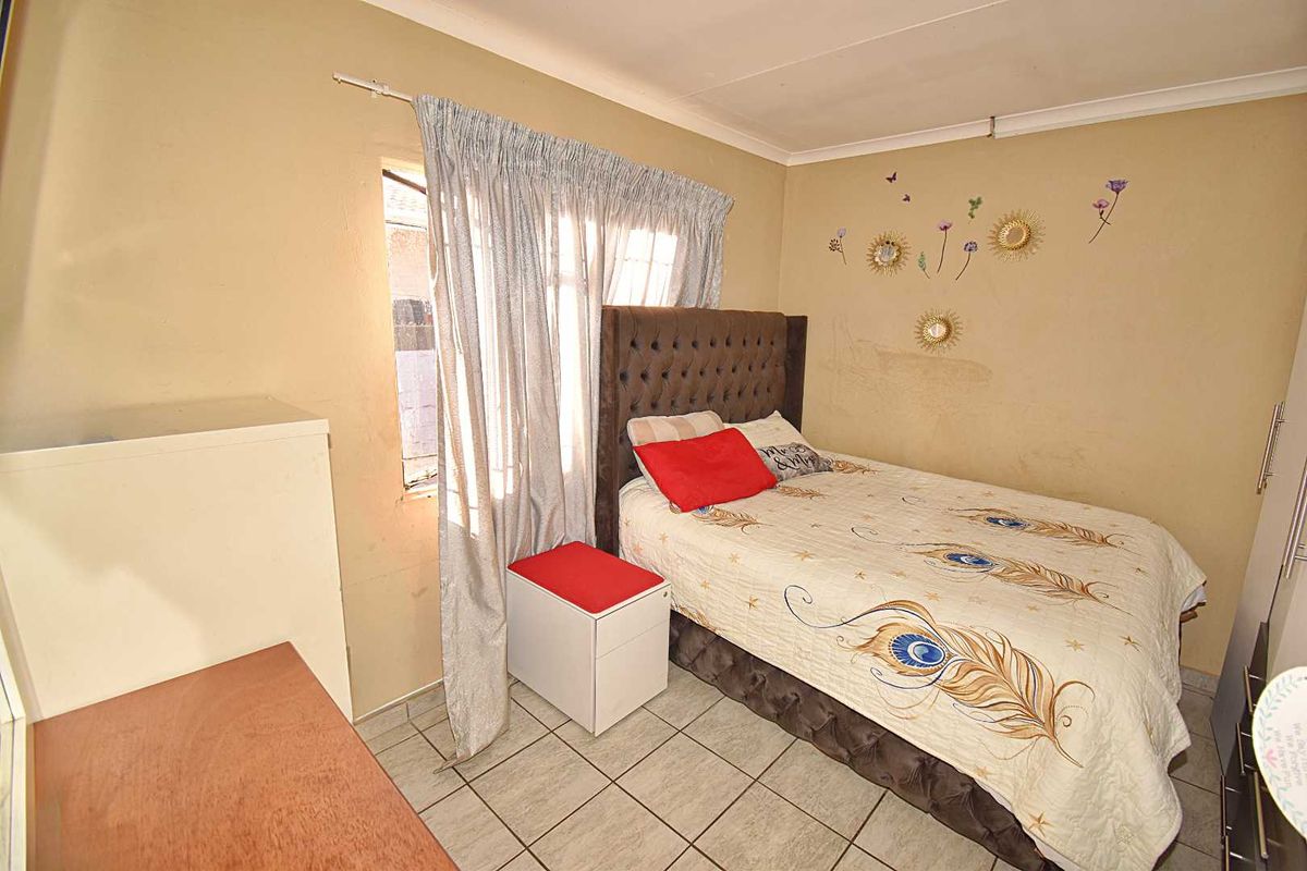 A bedroom featuring tiled flooring and coved ceilings, currently requiring cosmetic updates to the wall finishes.