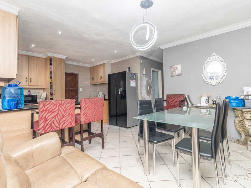 Open-plan kitchen and dining area featuring tiled flooring, built-in cabinetry, and recessed lighting, requiring some cosmetic wall repairs.