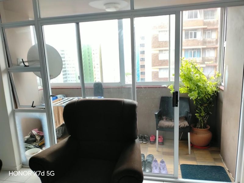 Enclosed balcony area featuring sliding glass doors and tiled flooring, offering a functional outdoor space with urban views.