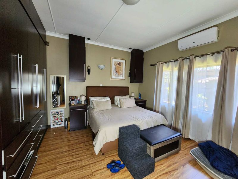 A well-maintained bedroom featuring laminate flooring, extensive built-in cabinetry, and a wall-mounted air conditioning unit.