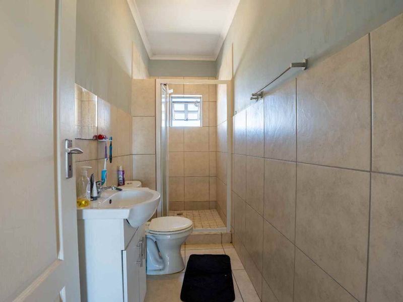 A functional bathroom featuring a pedestal washbasin, toilet, and a separate shower enclosure with tiled walls and flooring.