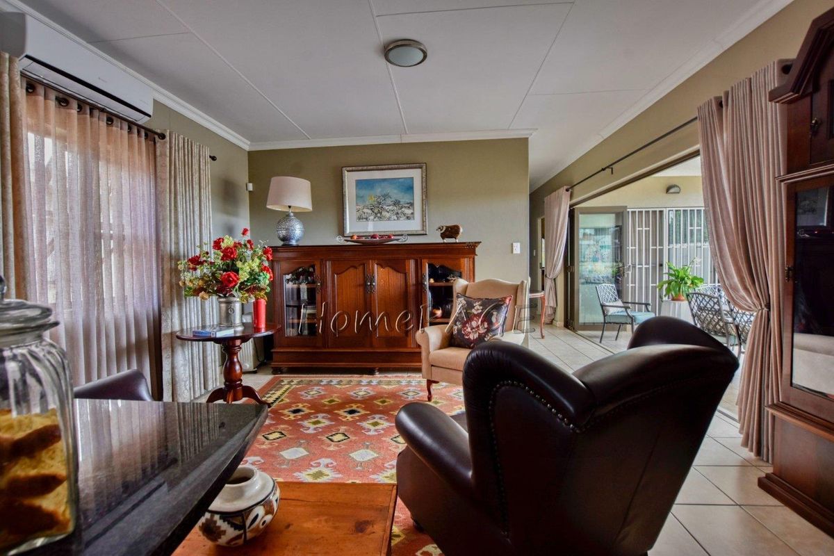 A comfortable living room featuring tiled flooring, a wall-mounted air conditioning unit, and large sliding doors leading to an outdoor patio area.