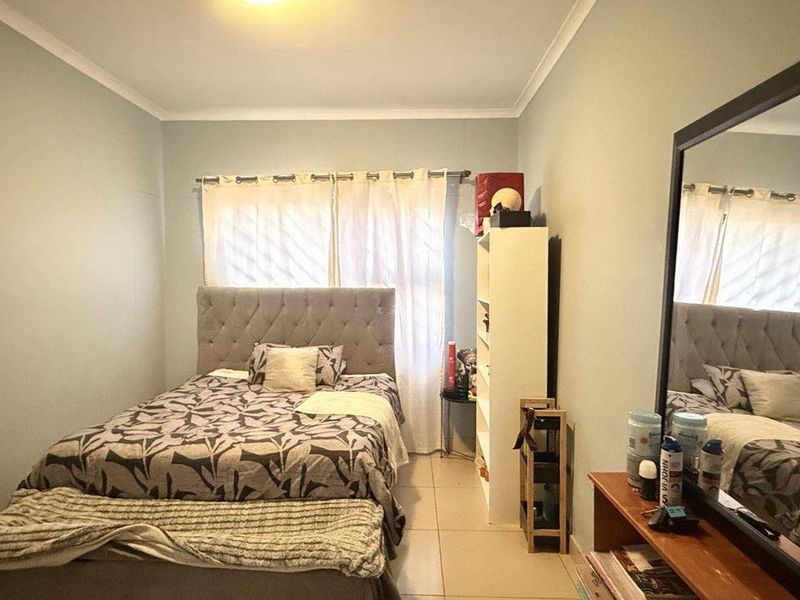 A standard bedroom featuring tiled flooring and neutral wall finishes, providing a functional space with natural light from the window.