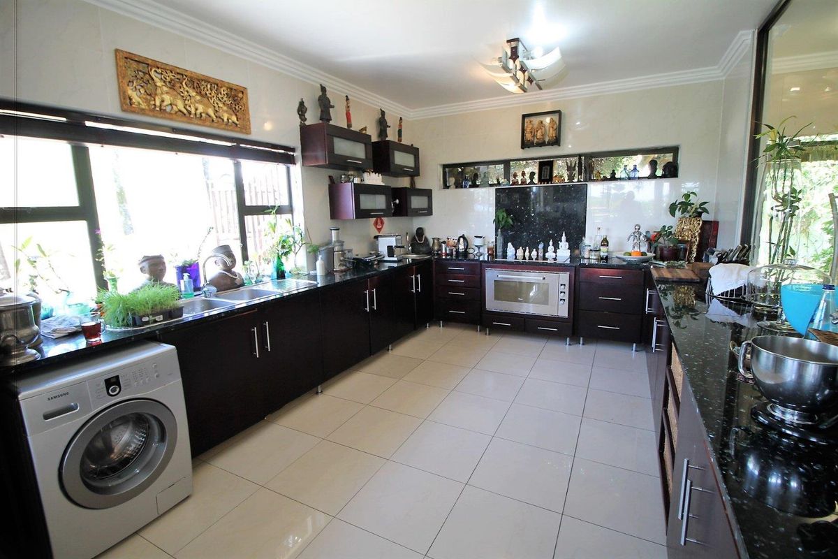 Spacious kitchen featuring dark wood cabinetry, granite countertops, built-in oven, and integrated laundry facilities with large windows providing ample natural light.