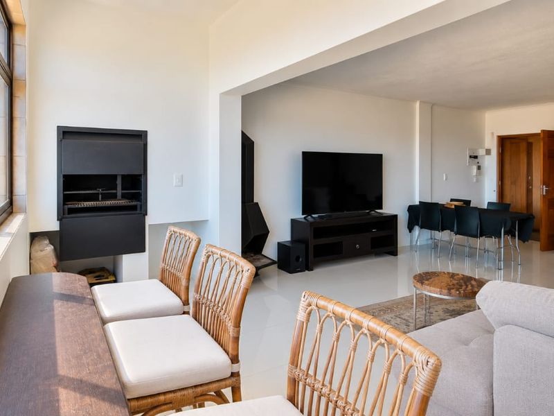 Spacious open-plan living and dining area featuring tiled floors, a built-in braai, and large windows offering scenic coastal views.