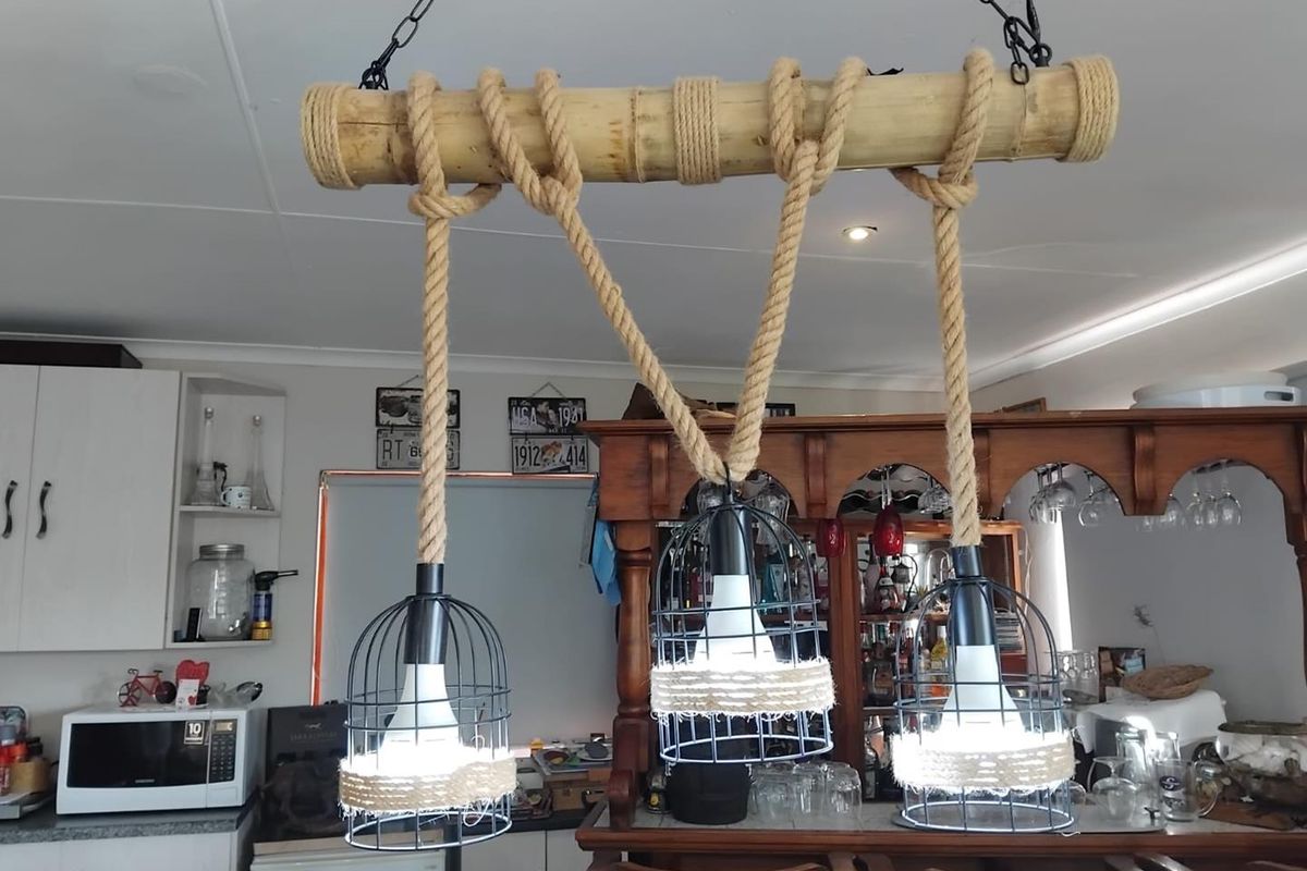 A kitchen area featuring a rustic rope and bamboo pendant light fixture suspended above a wooden bar counter.