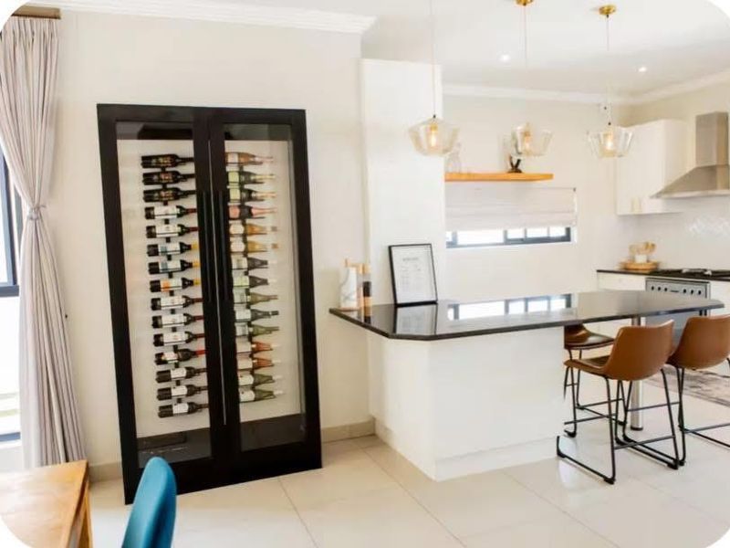Modern open-plan kitchen featuring a sleek island, contemporary pendant lighting, and a dedicated built-in wine display cabinet.
