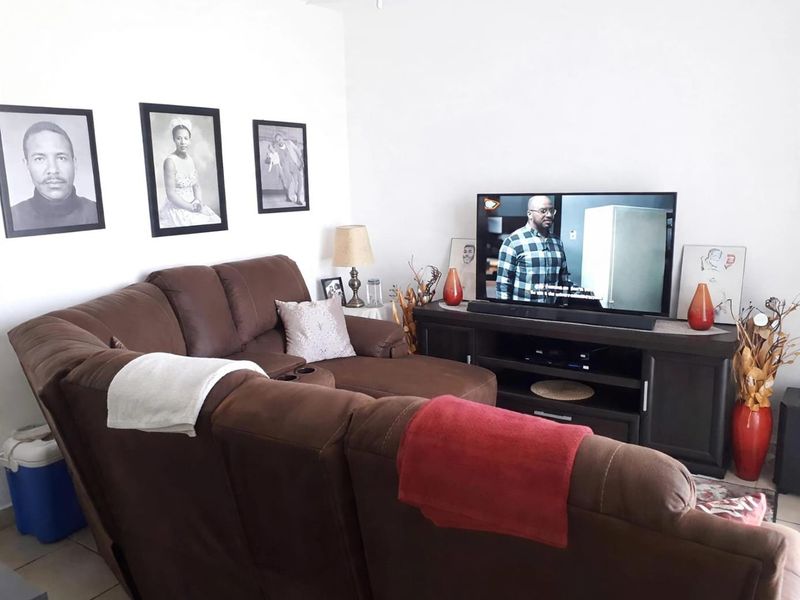 A comfortable living room area featuring neutral walls and tiled flooring, providing a functional space for relaxation and entertainment.