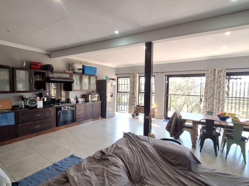 Spacious open-plan kitchen and dining area featuring dark wood cabinetry, tiled floors, and large sliding doors leading to a balcony with natural light.