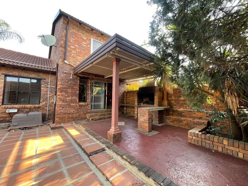 A covered outdoor patio area featuring a built-in brick braai, concrete flooring, and direct access to the main dwelling.