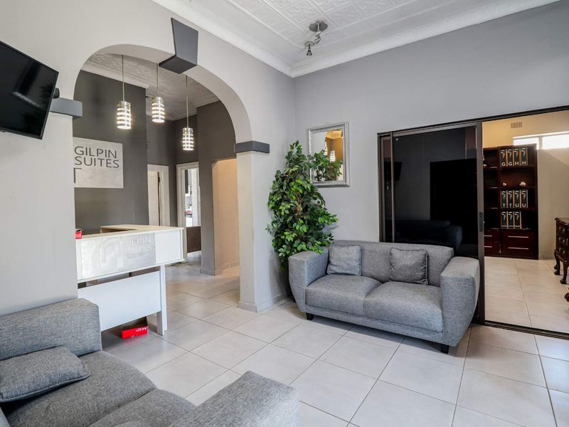 A professional office reception area featuring a built-in reception desk, arched architectural detailing, tiled flooring, and a sliding glass door leading to an office.