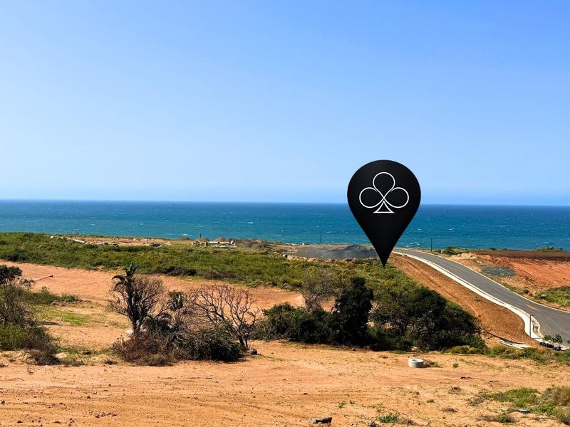 An aerial view of a vacant residential plot featuring coastal views and access to a paved road.
