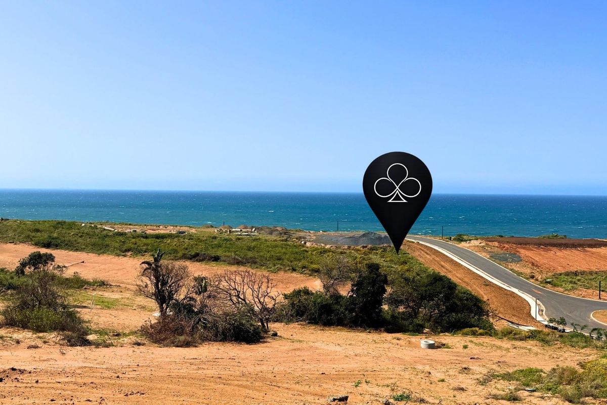 An aerial view of a vacant residential plot featuring coastal views and access to a paved road.