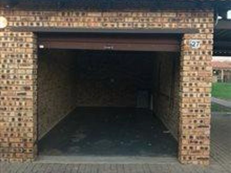 A single-car garage featuring face brick construction, a tiled roof, and a concrete floor, providing secure parking or storage space.