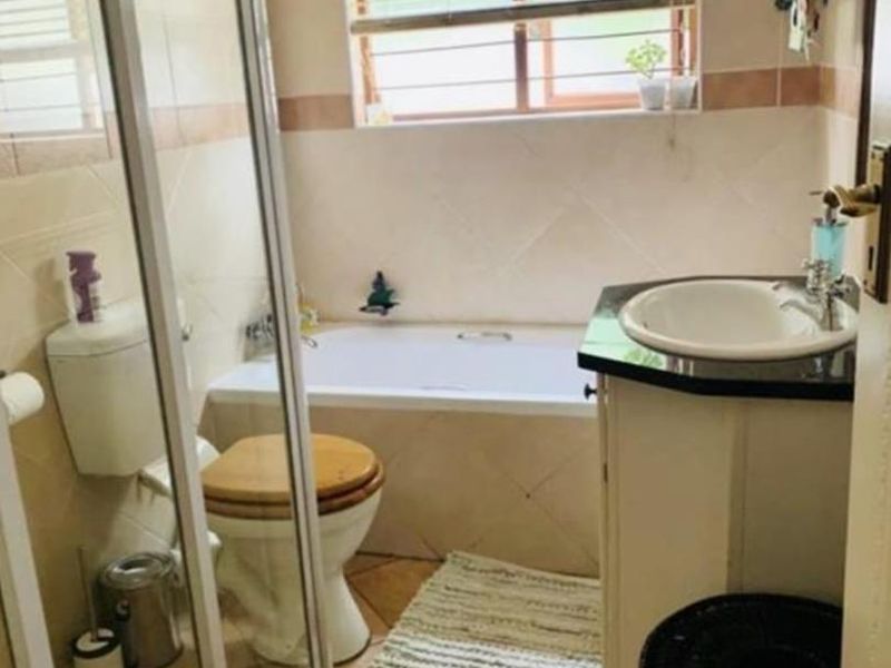 A functional bathroom featuring a built-in vanity with basin, a bathtub, a separate shower enclosure, and tiled finishes throughout.